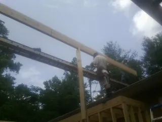 Carpenter setting a ridge beam over a new addition frame — Ice Dam Removal by Roofing Brothers in Huxley