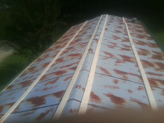 Rusted metal roof panels with new wood purlins before replacement — Storm Damage Roof Repair in Huxley by Roofing Brothers