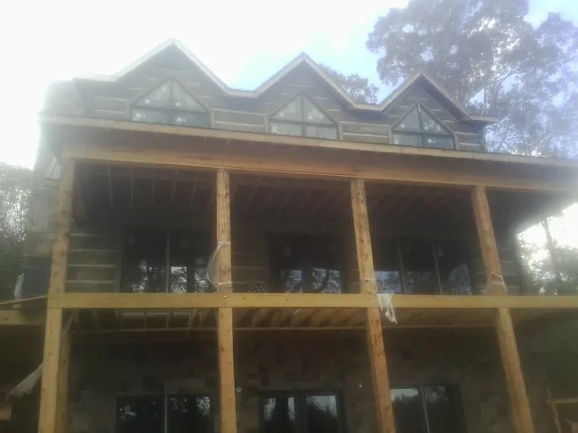 Dormers and porch framing on a large log home under construction — Roof Coating work by our crew in Huxley