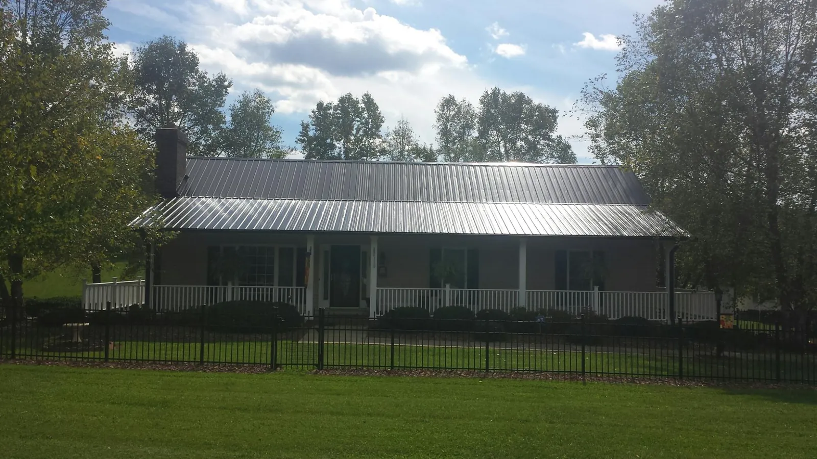 Gray metal roof on a brick ranch with a full width front porch — Gutter Guard Installation work by our crew in Huxley
