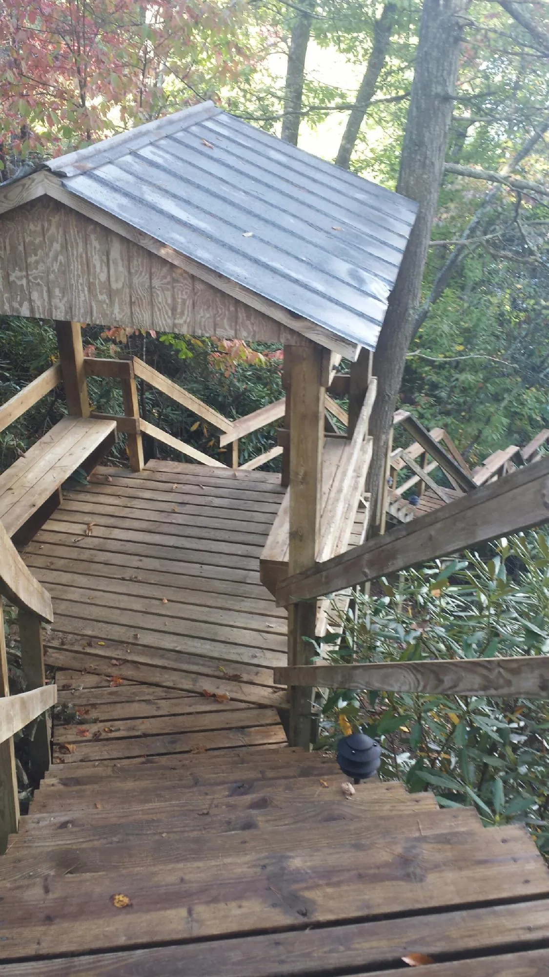 Metal roofed shelter over wooden steps on a wooded walkway — Skylight Repair & Installation work by our crew in Huxley