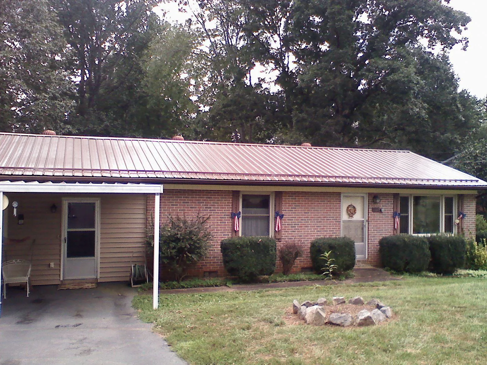 Bronze metal roof and carport on a brick ranch home — Roof Repair work by our crew in Huxley